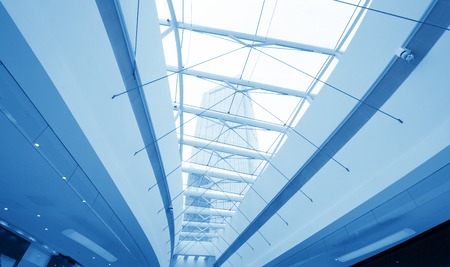 Underside wide angled and perspective view to steel blue glass airport ceiling through high rise building skyscrapers, business concept of successful industrial architectureのeditorial素材