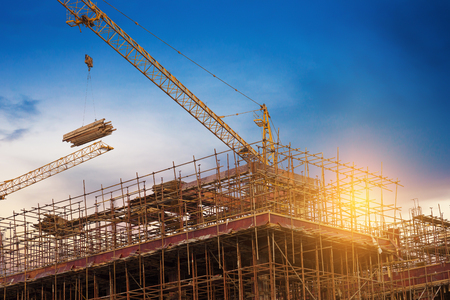 Construction site, silhouettes of construction industry workers on scaffolding against the sunset light.の写真素材