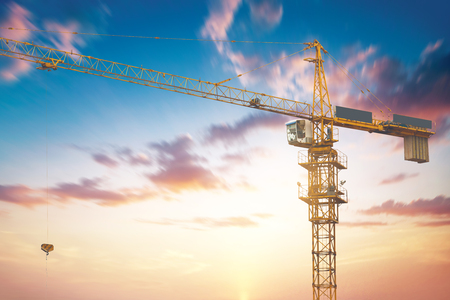 Abstract Industrial background with construction cranes silhouettes over amazing sunset skyの写真素材