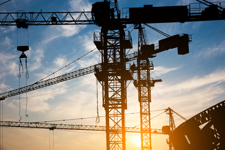 Abstract Industrial background with construction cranes silhouettes over amazing sunset skyの写真素材