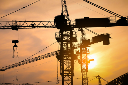 Abstract Industrial background with construction cranes silhouettes over amazing sunset skyの写真素材