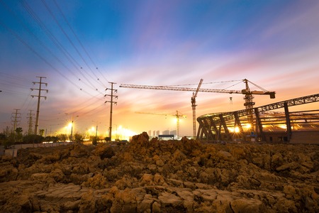 Lots of tower cranes build large residential buildings at night.