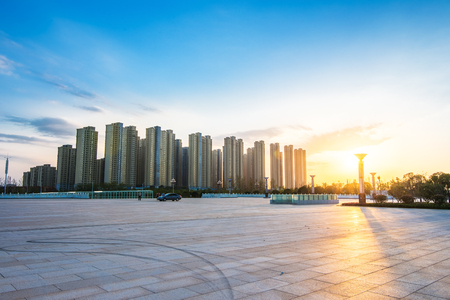 empty asphalt road with trees aside and skyscrapers under sunbeamの写真素材