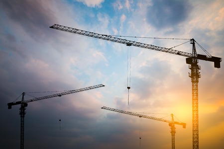 Abstract Industrial background with construction cranes silhouettes over amazing sunset skyの写真素材