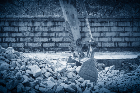 heavy organge excavator with shovel standing on hill with rocks