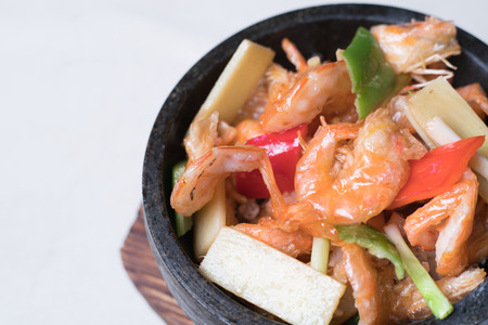 Shrimp stir fry in a wok with serving plates in the backgroundの写真素材