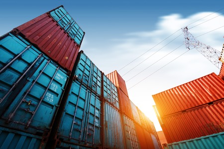 Forklift truck lifting cargo container in shipping yard or dock yard against sunrise sky with cargo container stack in background for transportation import,export and logistic industrial conceptのeditorial素材