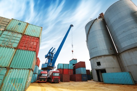 Forklift truck lifting cargo container in shipping yard or dock yard against sunrise sky with cargo container stack in background for transportation import,export and logistic industrial conceptのeditorial素材