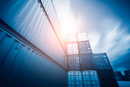Forklift truck lifting cargo container in shipping yard or dock yard against sunrise sky with cargo container stack in background for transportation import,export and logistic industrial conceptのeditorial素材