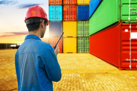 Dock worker talking on the walkie-talkie for controlling loading container in an industrial harborの写真素材