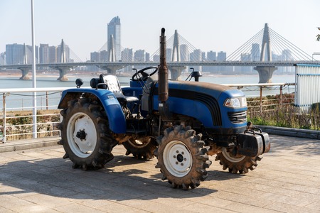 Blue tractor on the background of an empty field and a clear blue skyの写真素材