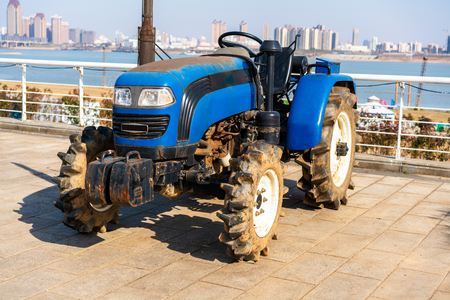 Blue tractor on the background of an empty field and a clear blue skyの写真素材