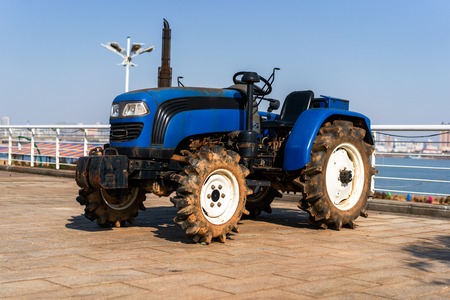 Blue tractor on the background of an empty field and a clear blue skyの写真素材