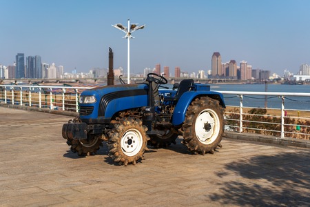 Blue tractor on the background of an empty field and a clear blue skyの写真素材