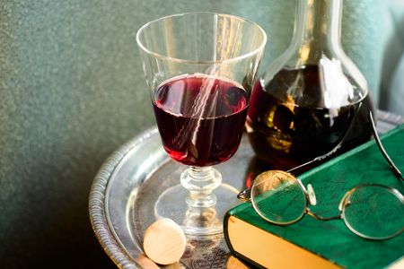 Bottle of red wine with book, eyeglasses,wineglass on a silver trayの写真素材