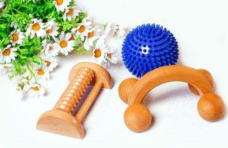 Massage utensils like roller,ball and flowers on white backgroundの写真素材