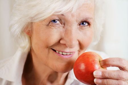 Happily senior woman holding red appleの写真素材
