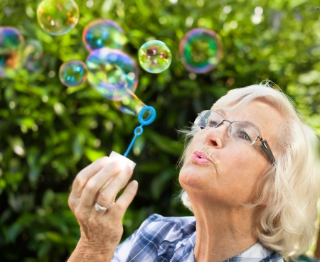 Senior woman is blowing bubbles in the garden,close-upの写真素材