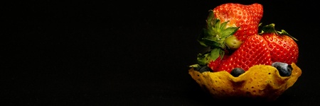 strawberries in ginger bread snap cookie basket on dark backgroundの写真素材