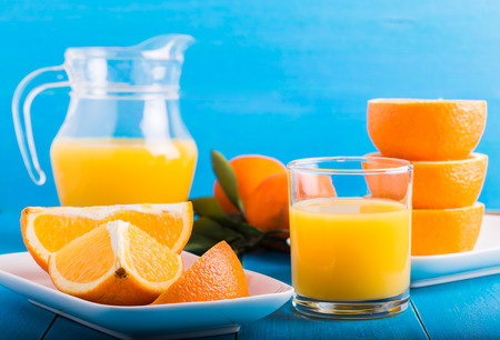 Fresh tangerines, oranges, orange juice on a blue backgroundの写真素材