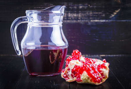 Pomegranate juice and pomegranate parts on a black backgroundの写真素材