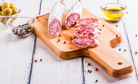 Slices of salami on a cutting board in a rustic styleの写真素材