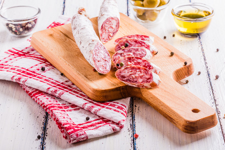 Slices of salami on a cutting board in a rustic styleの写真素材