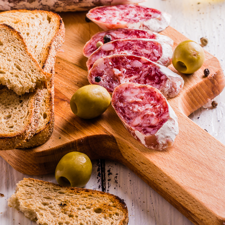 Slices of salami on a cutting board in a rustic styleの写真素材