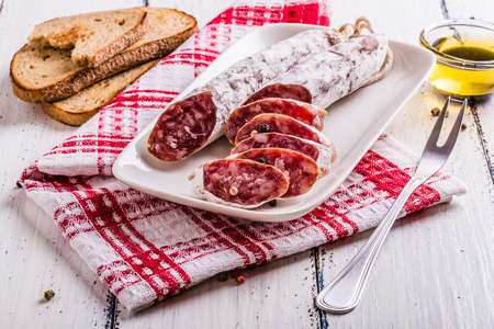 Slices of salami on a white plate in a rustic styleの写真素材