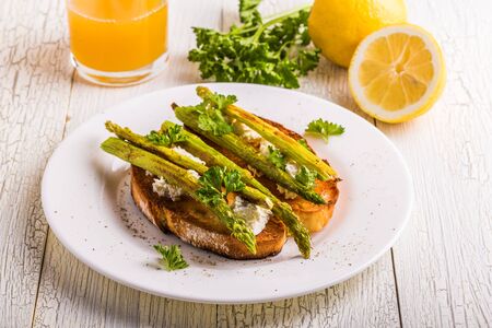 Bruschetta with goat cheese and grilled asparagus on a white wooden background.の写真素材