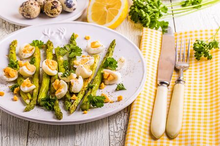 Grilled asparagus with quail eggs on a white wooden backgroundの写真素材