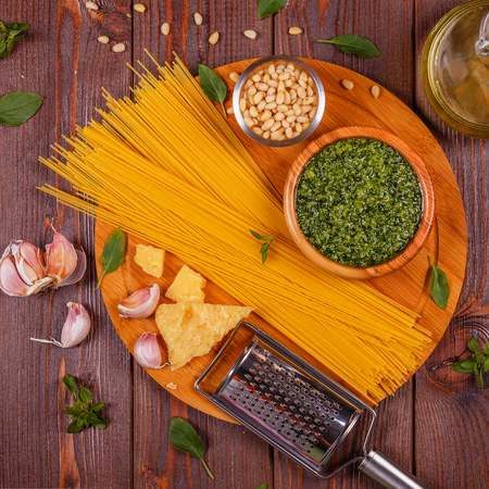 Green basil pesto - italian recipe ingredients on wooden table, top view.の写真素材