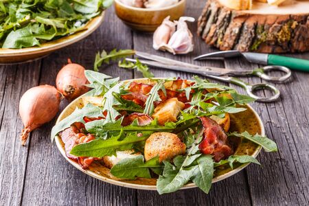 Fresh dandelion salad with fried bacon and garlic croutons, rustic style, selective focus.の写真素材