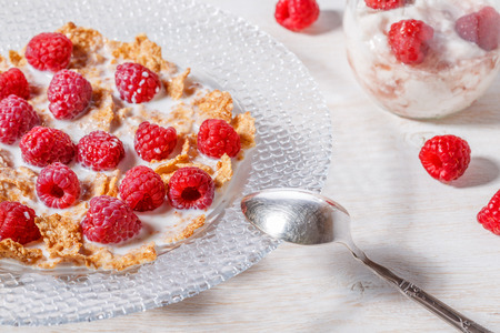 Wheat flakes with raspberries and milk, selective focus.の写真素材