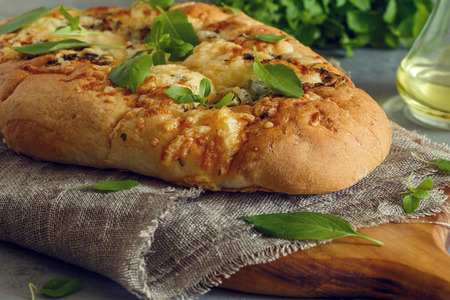 Focaccia with onions, herbs and cheese, garnished with basil leaves.の写真素材