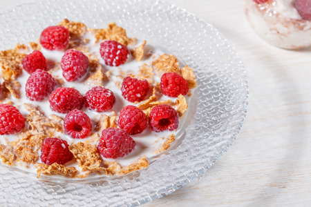 Wheat flakes with raspberries and milk, selective focus.