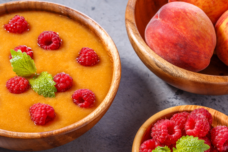 Refreshing cold peach soup garnished with raspberries and mint leaves, selective focus.の写真素材