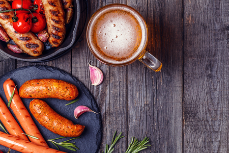 Grilled sausages with glass of beer on wooden table. Top view with copy space.の写真素材