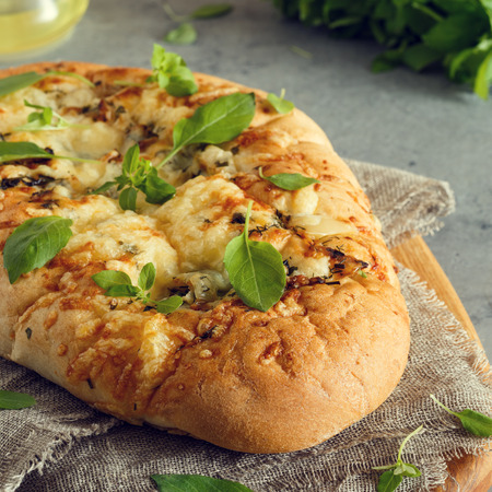 Focaccia with onions, herbs and cheese, garnished with basil leaves.の写真素材