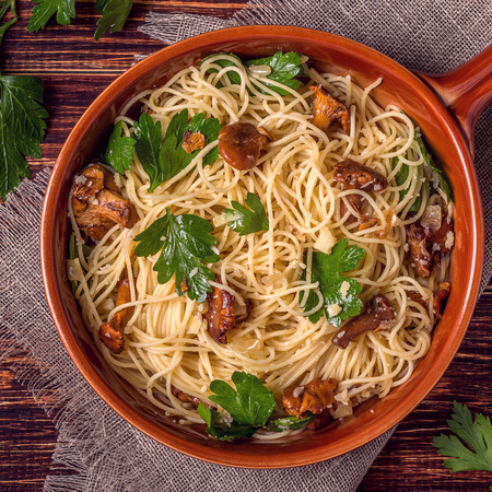 Pasta spaghetti with chanterelles mushrooms on wooden background, top view.の写真素材