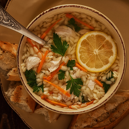 Chicken soup with pasta on a dark wooden background, top view.の写真素材