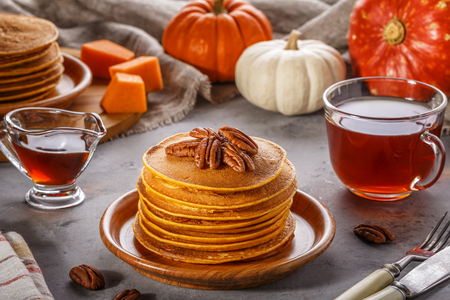 Stack of homemade pumpkin pancakes with pecans and maple syrup, selective focus.の写真素材