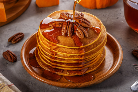 Stack of homemade pumpkin pancakes with pecans and maple syrup, selective focus.の写真素材