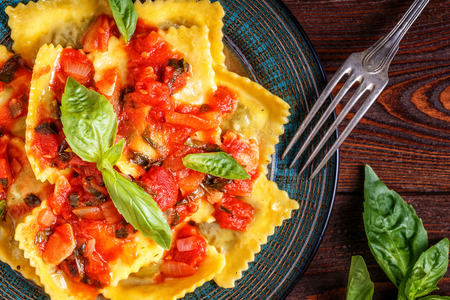 Ravioli with tomato sauce and basil on dark background, top view.の写真素材