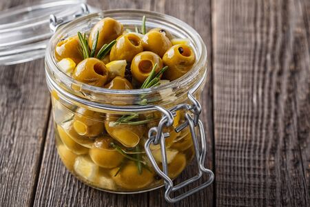 Fresh olives with rosemary, garlic, lemon and olive oil on rustic wooden background.の写真素材
