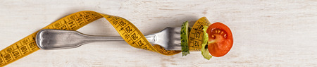 Fresh salad on a fork, tape measure, top view. The concept of diet, healthy foodの写真素材