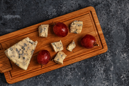 Pieces of blue cheese on wooden serving board, top view.の写真素材