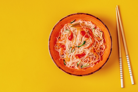 Glass noodle salad with cucumber pepper and carrot on a bright pastel background, top view.の写真素材