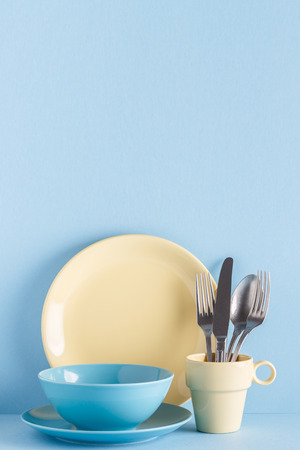 Crockery and cutlery on a blue pastel background with copy space.の写真素材