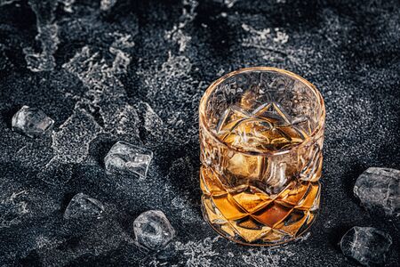 Whiskey with ice on a stone dark background.の写真素材